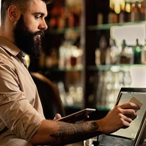 Image d'un serveur travaillant sur l'interface du système d'encaissement dans un restaurant, illustrant le service informatique de déploiement numérique proposé par Inibar Services.